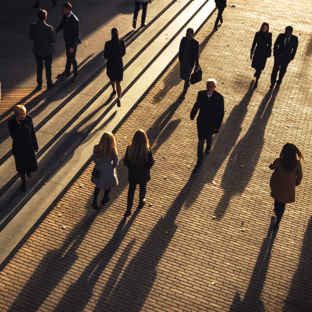 aerial photo of people walking and seeing their shadows